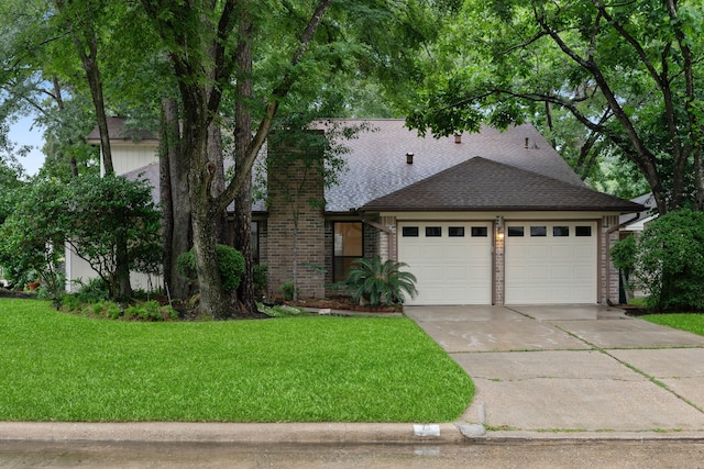 71 Timberspire Ln, The Woodlands, TX 77380 - view of front facade featuring an attached garage, a front yard, concrete driveway, brick siding, and roof with shingles