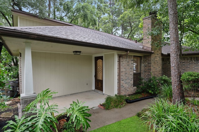 71 Timberspire Ln, The Woodlands, TX 77380 - doorway to property with a chimney, a shingled roof, and brick siding