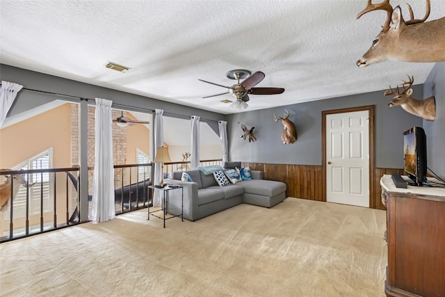 20131 Magnolia Bend Dr, Humble, TX 77346 - living room with ceiling fan, a wainscoted wall, light colored carpet, a textured ceiling, and wooden walls