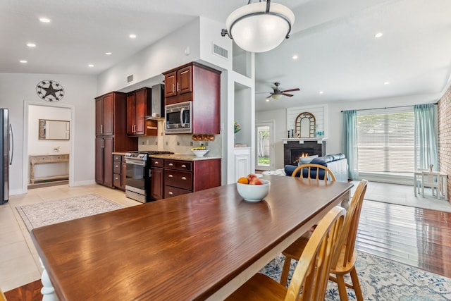 9123 Kapri Ln, Houston, TX 77025 - dining room with a lit fireplace, ceiling fan, recessed lighting, baseboards, and light tile patterned floors