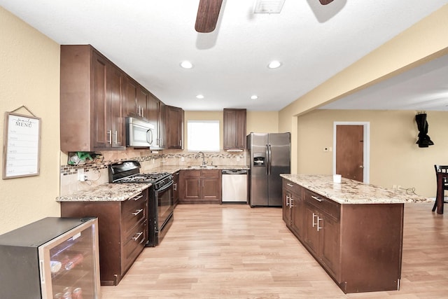 5423 Lillian St, Baytown, TX 77521 - kitchen featuring stainless steel appliances, a ceiling fan, wine cooler, light wood-style floors, and a sink
