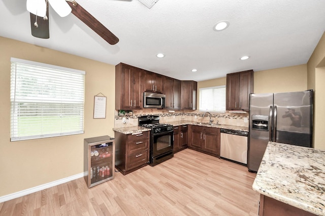 5423 Lillian St, Baytown, TX 77521 - kitchen featuring appliances with stainless steel finishes, beverage cooler, backsplash, a sink, and light wood-type flooring