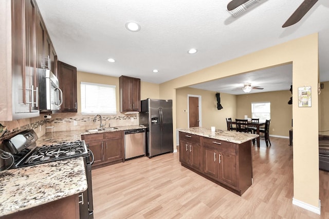 5423 Lillian St, Baytown, TX 77521 - kitchen with appliances with stainless steel finishes, a ceiling fan, a sink, light wood-style floors, and a center island