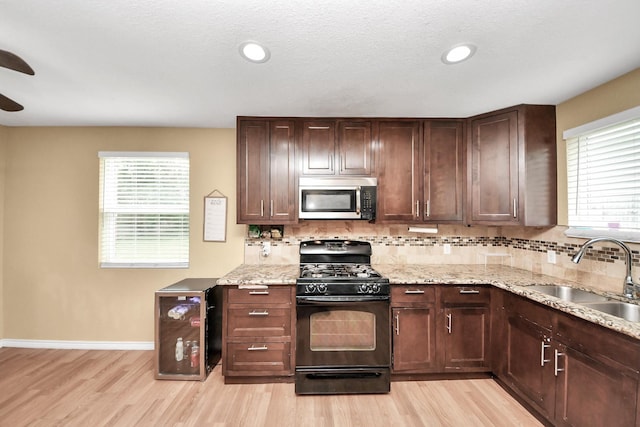 5423 Lillian St, Baytown, TX 77521 - kitchen with stainless steel microwave, black gas stove, wine cooler, a sink, and backsplash