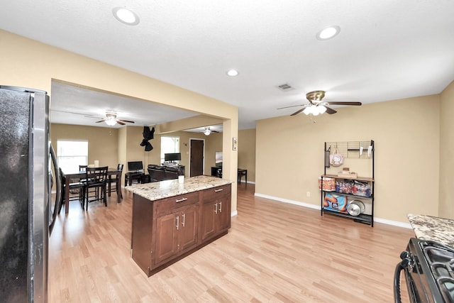 5423 Lillian St, Baytown, TX 77521 - kitchen with freestanding refrigerator, ceiling fan, black gas range, open floor plan, and light wood-style flooring