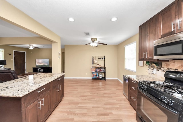 5423 Lillian St, Baytown, TX 77521 - kitchen with black gas range, stainless steel microwave, ceiling fan, open floor plan, and light wood-style flooring