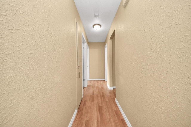 5423 Lillian St, Baytown, TX 77521 - hallway featuring a textured wall, light wood-style flooring, and baseboards