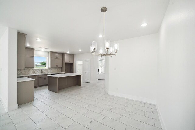 702 Azalea St, Prairie View, TX 77484 - kitchen with gray cabinets, backsplash, a center island, a sink, and light countertops