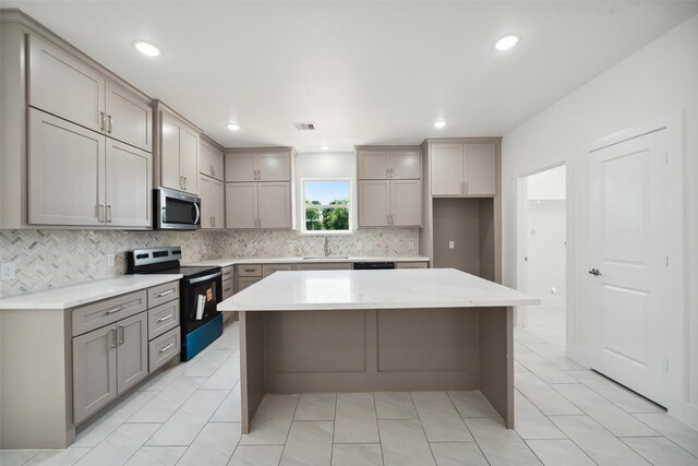 702 Azalea St, Prairie View, TX 77484 - kitchen featuring electric range oven, stainless steel microwave, gray cabinets, a sink, and decorative backsplash