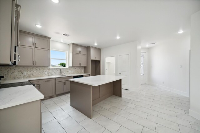 702 Azalea St, Prairie View, TX 77484 - kitchen featuring stove, a sink, gray cabinetry, backsplash, and a kitchen island