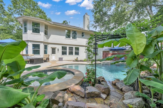 14 Terrell Trail Ct, The Woodlands, TX 77385 - back of property featuring a chimney, a patio area, and a pool with connected hot tub