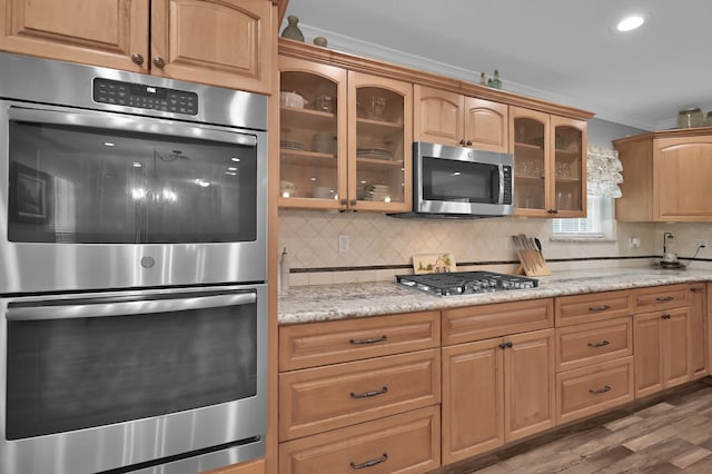 833 Stone Mountain Dr, Conroe, TX 77302 - kitchen with appliances with stainless steel finishes, tasteful backsplash, ornamental molding, glass insert cabinets, and wood finished floors