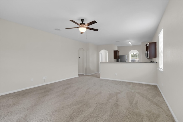 7571 Fettle Ln, Conroe, TX 77304 - unfurnished living room with arched walkways, ceiling fan, light colored carpet, and baseboards