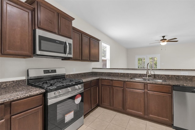 7571 Fettle Ln, Conroe, TX 77304 - kitchen with appliances with stainless steel finishes, a sink, a ceiling fan, light tile patterned floors, and dark brown cabinetry