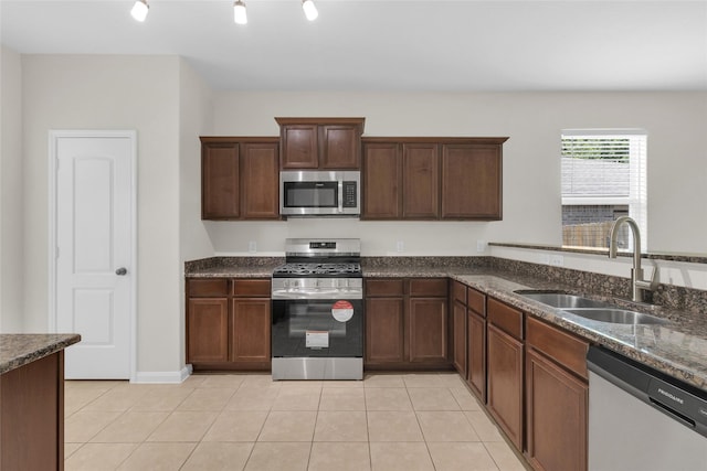 7571 Fettle Ln, Conroe, TX 77304 - kitchen with appliances with stainless steel finishes, a sink, dark stone countertops, and light tile patterned flooring
