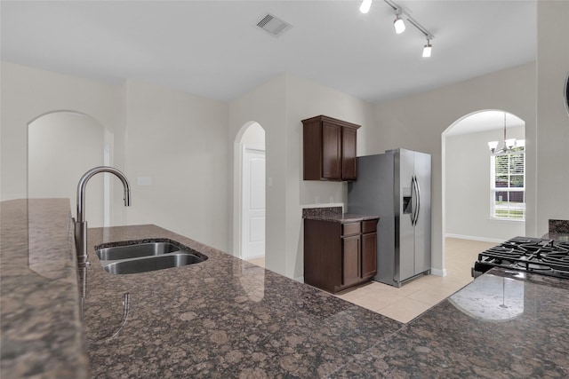 7571 Fettle Ln, Conroe, TX 77304 - kitchen with stainless steel fridge, a sink, arched walkways, dark stone countertops, and light tile patterned floors