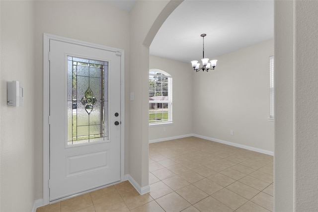 7571 Fettle Ln, Conroe, TX 77304 - foyer entrance featuring light tile patterned floors, a chandelier, arched walkways, and baseboards