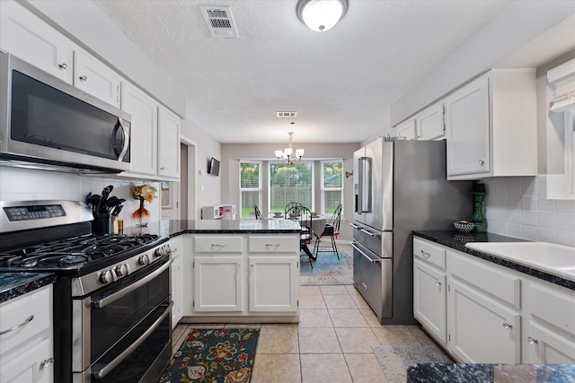 30307 Thorsby Dr, Spring, TX 77386 - kitchen with appliances with stainless steel finishes, a peninsula, white cabinetry, a chandelier, and decorative backsplash