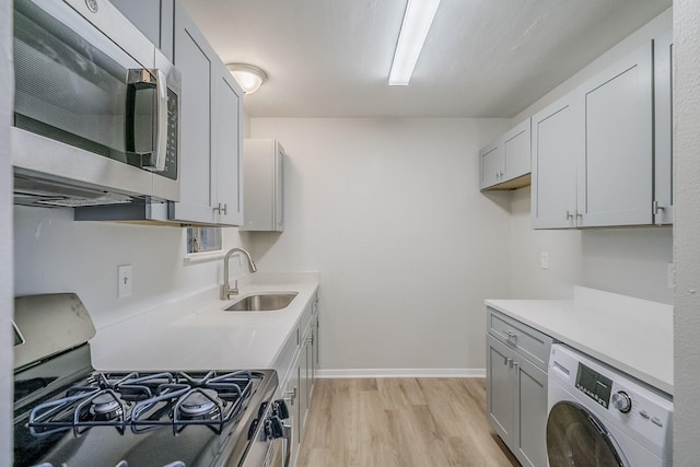 11063 Vailview Dr, Houston, TX 77016 - kitchen featuring washer / dryer, stainless steel microwave, gas range, a sink, and light wood-style flooring