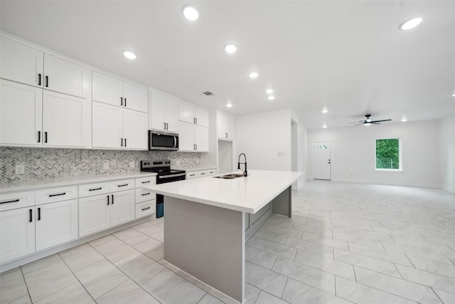 708 Azalea St, Prairie View, TX 77484 - kitchen featuring stainless steel appliances, a sink, a ceiling fan, backsplash, and a center island with sink