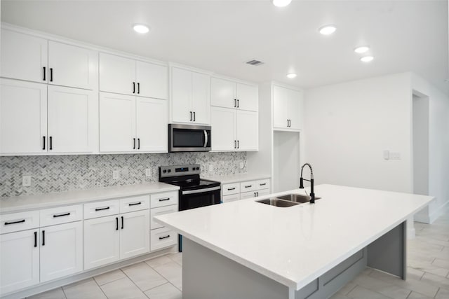 708 Azalea St, Prairie View, TX 77484 - kitchen featuring stainless steel microwave, a sink, range with electric cooktop, tasteful backsplash, and an island with sink