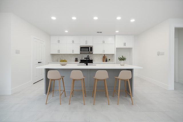 708 Azalea St, Prairie View, TX 77484 - kitchen featuring stainless steel appliances, a center island with sink, backsplash, recessed lighting, and white cabinets