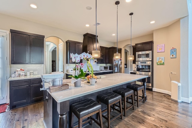 7203 Prairie Grass Ln, Katy, TX 77493 - kitchen featuring arched walkways, appliances with stainless steel finishes, tasteful backsplash, dark wood-style flooring, and recessed lighting