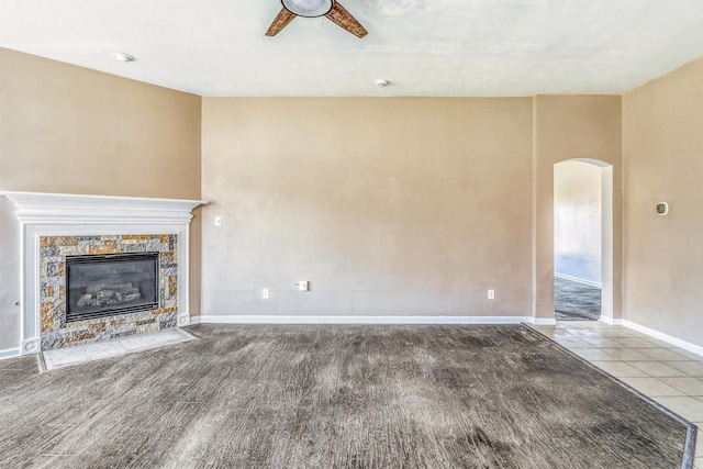 7523 Chathan Glen Ln, Richmond, TX 77407 - unfurnished living room with arched walkways, a ceiling fan, a stone fireplace, baseboards, and wood finished floors