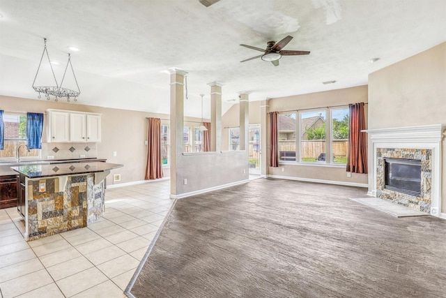 7523 Chathan Glen Ln, Richmond, TX 77407 - unfurnished living room with ceiling fan, a fireplace, baseboards, light tile patterned floors, and a sink