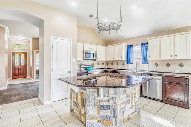 7523 Chathan Glen Ln, Richmond, TX 77407 - kitchen with appliances with stainless steel finishes, a sink, arched walkways, light tile patterned flooring, and white cabinets