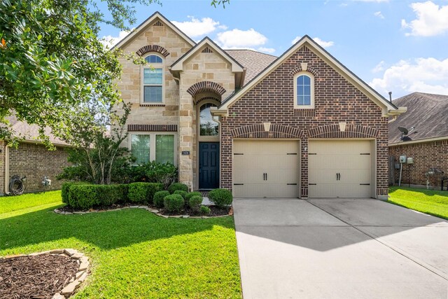 1406 Kallie Hills Ln, Spring, TX 77386 - french country inspired facade featuring stone siding, concrete driveway, a front lawn, and brick siding