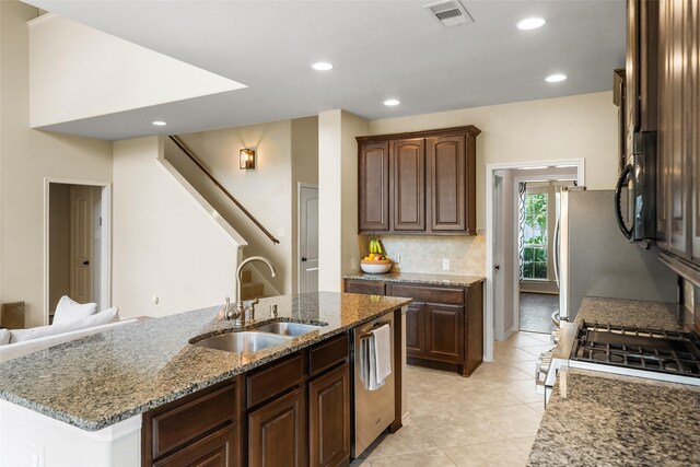 1406 Kallie Hills Ln, Spring, TX 77386 - kitchen featuring a sink, appliances with stainless steel finishes, stone counters, tasteful backsplash, and light tile patterned flooring