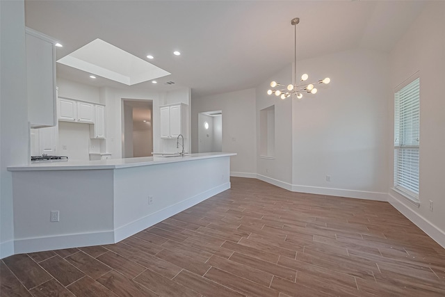 4046 Dell Ln, Missouri City, TX 77459 - kitchen featuring wood finished floors, white cabinetry, a peninsula, lofted ceiling, and a chandelier