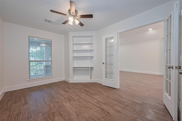4046 Dell Ln, Missouri City, TX 77459 - empty room featuring french doors, built in shelves, a ceiling fan, and wood finished floors