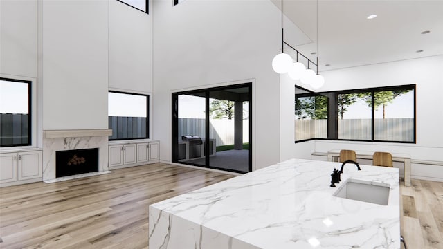 207 W 33rd St, Houston, TX 77018 - kitchen featuring a sink, light wood finished floors, plenty of natural light, light stone counters, and a towering ceiling
