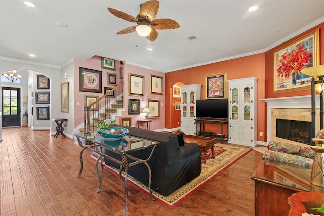 18 Brookefield Cir, Magnolia, TX 77355 - living room featuring a fireplace, arched walkways, stairway, wood finished floors, and crown molding
