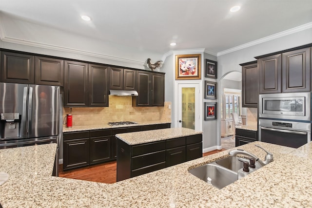 18 Brookefield Cir, Magnolia, TX 77355 - kitchen with stainless steel appliances, crown molding, a sink, arched walkways, and light stone counters