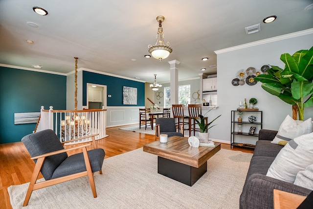 902 Cohn St, Houston, TX 77007 - living area with ornamental molding, light wood-style flooring, ornate columns, a chandelier, and wainscoting