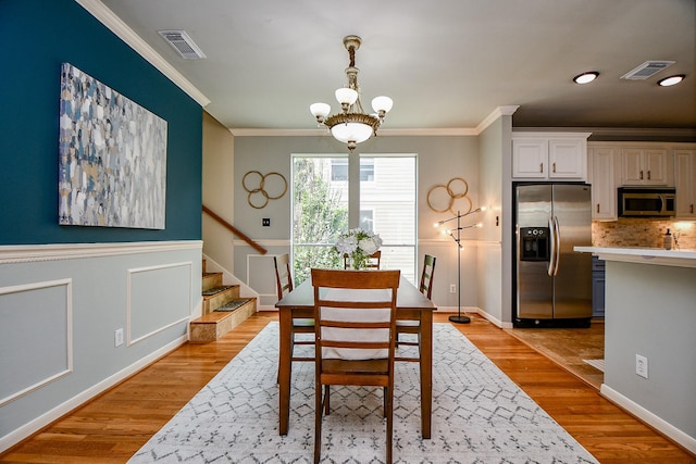 902 Cohn St, Houston, TX 77007 - dining area featuring a chandelier, crown molding, light wood finished floors, stairs, and a wainscoted wall