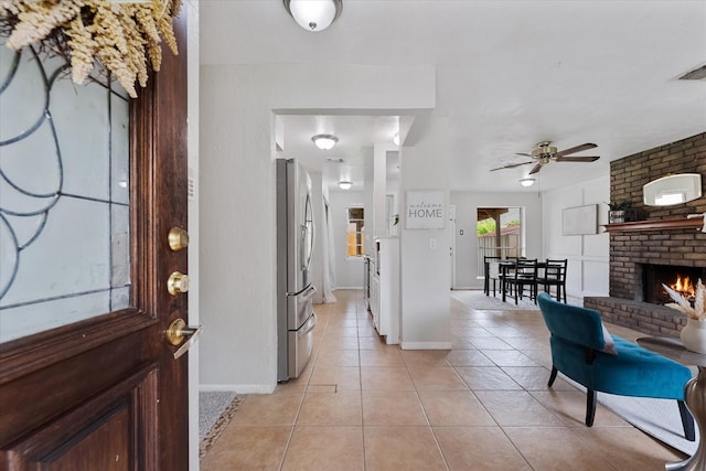 11731 Bexar Dr, La Porte, TX 77571 - entrance foyer with light tile patterned floors, a fireplace, a ceiling fan, and baseboards