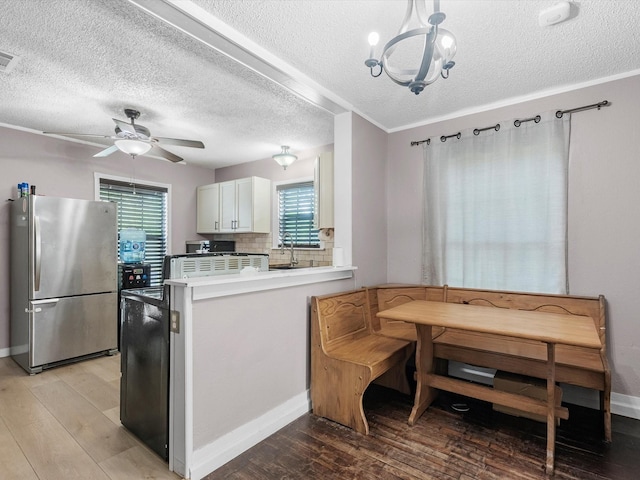 809 18th Ave N, Texas City, TX 77590 - kitchen featuring freestanding refrigerator, light wood-style floors, a peninsula, a textured ceiling, and a chandelier