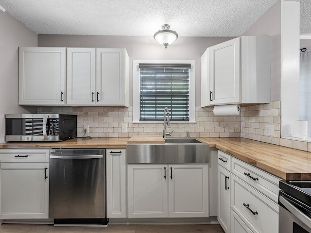 809 18th Ave N, Texas City, TX 77590 - kitchen with stainless steel appliances, wooden counters, a sink, a textured ceiling, and backsplash