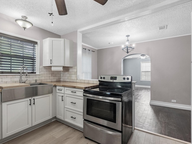 809 18th Ave N, Texas City, TX 77590 - kitchen with stainless steel electric range oven, a ceiling fan, a sink, white cabinets, and a textured ceiling