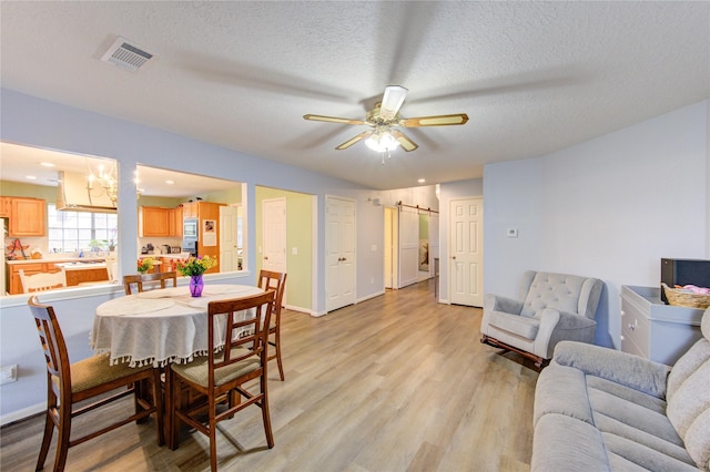 3402 Deeds Rd, Houston, TX 77084 - dining space featuring a barn door, light wood finished floors, a ceiling fan, a textured ceiling, and baseboards