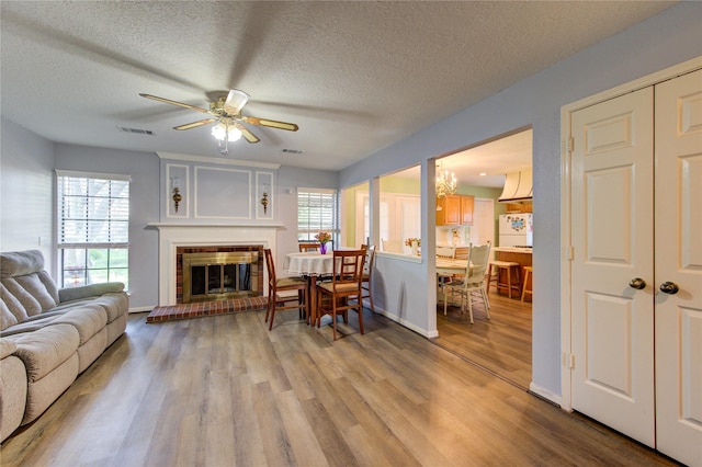 3402 Deeds Rd, Houston, TX 77084 - living room with healthy amount of natural light, wood finished floors, a brick fireplace, ceiling fan, and a textured ceiling