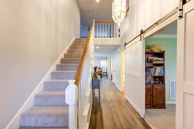 3402 Deeds Rd, Houston, TX 77084 - staircase featuring a barn door, wood finished floors, a towering ceiling, and baseboards