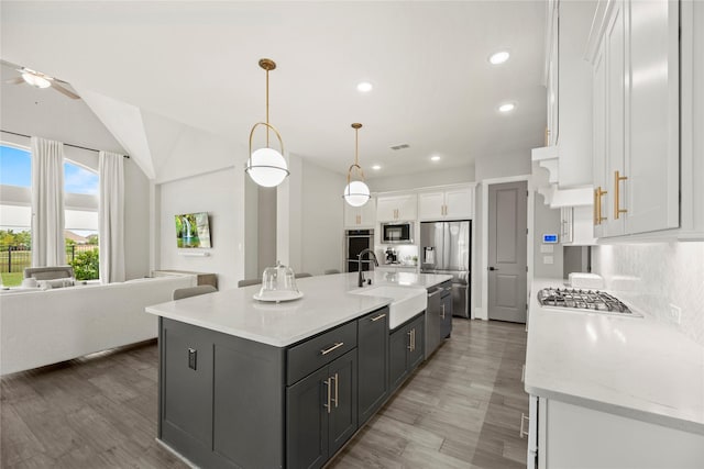 19307 Spillway Overlook Cir, Cypress, TX 77433 - kitchen with white cabinetry, open floor plan, light wood-style flooring, appliances with stainless steel finishes, and backsplash