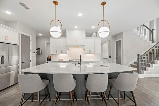 19307 Spillway Overlook Cir, Cypress, TX 77433 - kitchen featuring appliances with stainless steel finishes, light wood finished floors, a large island with sink, white cabinets, and recessed lighting