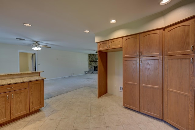 906 Carlee Dr, Brenham, TX 77833 - kitchen with light colored carpet, recessed lighting, a ceiling fan, brown cabinetry, and light stone counters