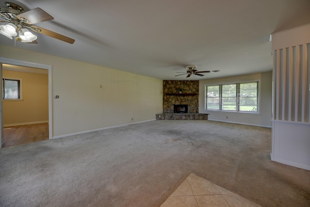 906 Carlee Dr, Brenham, TX 77833 - unfurnished living room with a ceiling fan, light colored carpet, a stone fireplace, and baseboards